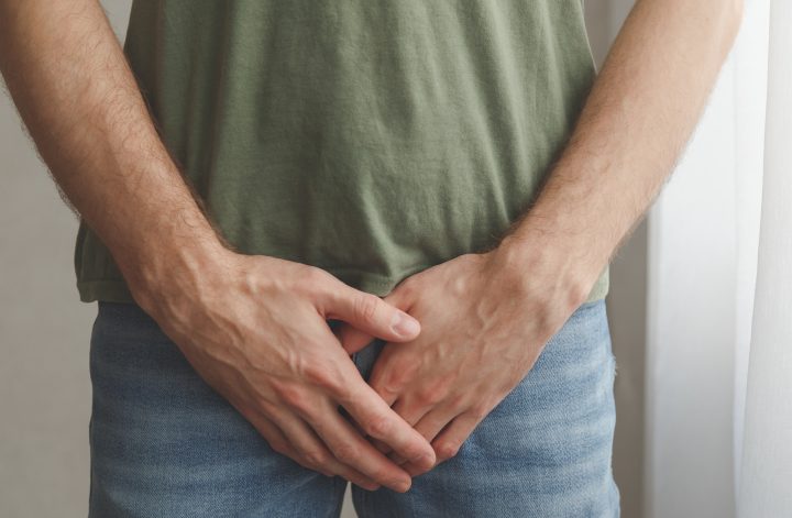 Muž si rukama zakrývá rozkrok. Zdraví mužů's. Urologické problémy mužů. Fotografie v přirozeném světle